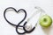 Alternative medicine healthy sign concept with stethoscope heart and green apple on white background