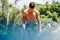 Althelte young man doing exercises on horizontal crossbar at sportsground. Handsome muscular shirtless male training hard,