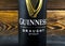 Aluminium can of Guinness draught stout beer bottle on dark wooden bar table. Guinness beer has been produced in Dublin, Ireland