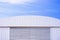 Aluminium louver on corrugated steel wall of warehouse building with curve metal roof against blue sky background