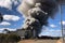 aluminium smelter, with towering smoke plume and flames leaping from stacks