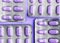 Aluminum blisters with colored purple oval tablets neat flat lay on a purple background
