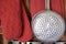 Aluminum colander hangs on the wall of a country house. Kitchen utensils, close-up.
