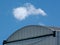 Aluminum exterior movie or airplane hangar building. blue sky and white clouds.