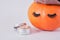 aluminum jar with cosmetic clay face mask and orange pumpkin with towel and false eyelashes on gray background