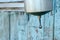 Aluminum washbasin hanging on peeling blue wooden wall