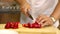 Amateur Cook cuts Bell pepper on wooden chopping board in kitchen close up