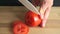 Amateur cooker slicing red tomato on bamboo cutting board