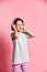 Amateur girl of music listens in white headphones, enjoying the pleasure of listening to music against a pink background