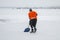 Amateur hockey player cleaning playground with shovel between game periods on a frozen river Dnipro in Ukraine