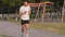 Amateur sportsman Indian guy runner in sportswear and sneakers runs on treadmill of stadium controlling time with
