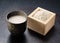 Amazake placed against a black background and rice koji in a masu box