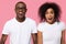 Amazed african couple feeling excited on pink studio background