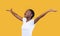 Amazed African Lady Spreading Raised Hands Looking Up, Yellow Background