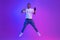 Amazed African Man Jumping Over Purple Neon Background And Pointing At Smartphone