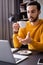 amazed arabian freelancer pointing at laptop while holding cup of coffee in restaurant, blurred foreground.