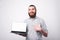 Amazed bearded man in casual pointing at white screen on laptop
