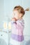 Amazed blond little girl with ponytail staying on bed