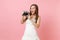 Amazed bride woman in wedding dress taking pictures on retro vintage photo camera choosing staff, photographer