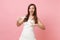 Amazed bride woman in white wedding dress pointing index finger on pregnancy test in hand on pink background