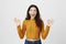 Amazed and cheerful young caucasian student raising hands with okay or fine signs, wearing trendy yellow sweater and