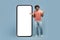 Amazed cool eastern guy posing by huge smartphone, mockup