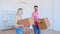 Amazed couple man and lady walk along new apartment room holding large cardboard boxes