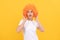 amazed fancy party look. freaky woman in clown wig on yellow background. express positive emotions.