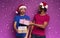 Amazed friends happy by the arrival of Christmas with present. Purple background