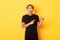 Amazed handsome korean guy, smiling fascinated and pointing fingers right, showing way, standing yellow background