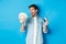 Amazed and happy man holding credit card, looking at money satisfied, standing over blue background