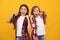 amazed kids in casual checkered shirt hold long straight hair on yellow background, hairstyle