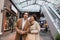amazed multiethnic couple with purchases walking