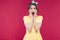 Amazed pinup girl in yellow dress standing with mouth opened