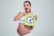 Amazed pregnant woman holding wall clock