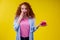 Amazed redhaired ginger curly woman holding gifts boxes and feeling shock emotions in studio yellow background