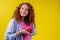 Amazed redhaired ginger curly woman holding gifts boxes and feeling shock emotions in studio yellow background