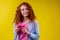 Amazed redhaired ginger curly woman holding gifts boxes and feeling shock emotions in studio yellow background