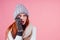 Amazed redhaired ginger woman wearing stylish hat ,knitted mittens and sweater gossiping in studio pink background