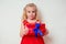 Amazed and surprised little girl in a Christmas red dress holding a gift and helium multi-colored balloons.christmas and