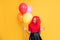amazed teen girl with party balloon on yellow background