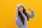 amazed teen girl wear earflap hat on yellow background, keep warm