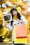 Amazed woman holding shopping bags and tablet in autumn