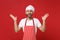 Amazed young male chef cook or baker man in striped apron white t-shirt toque chefs hat posing isolated on red