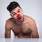 Amazed young naked man with red clown nose