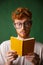 Amazed young red bearded student in glasses reading the notebook