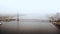 Amazing aerial panoramic shot of atmospheric old cable bridge, car traffic over epic Daugava river in Riga on foggy day.