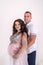 Amazing attractive and pregnant pair posing in studio near window