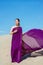 Amazing beautiful brunette woman with the Peacock feather in purple fabric in the desert.