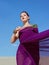 Amazing beautiful brunette woman with the Peacock feather in purple fabric in the desert.